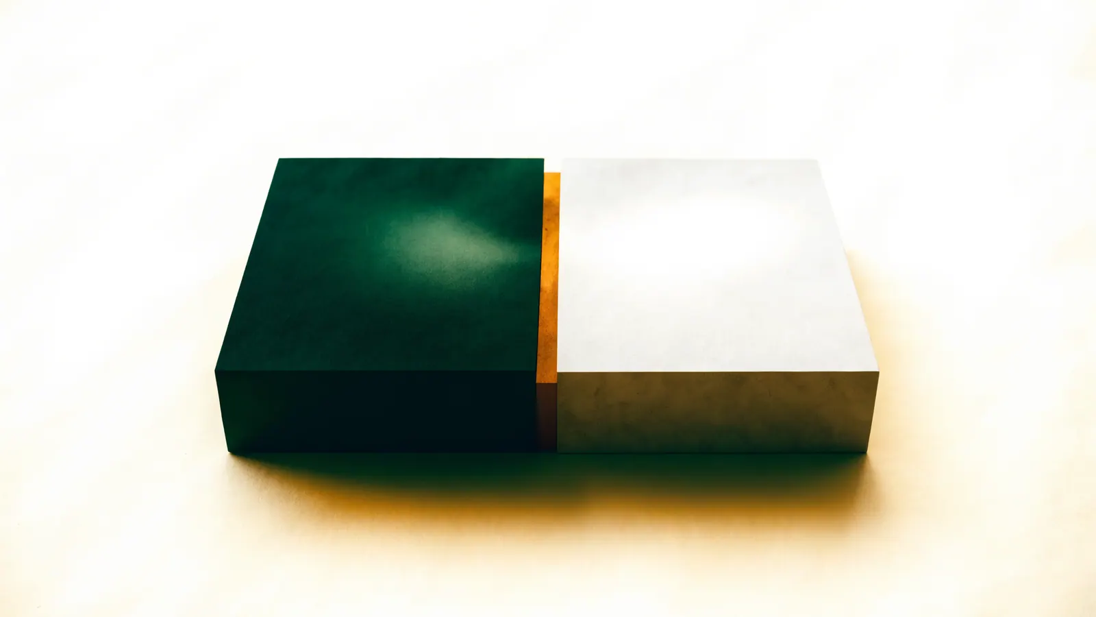 Two matte blocks, green and stone, meeting edge to edge with a narrow amber seam